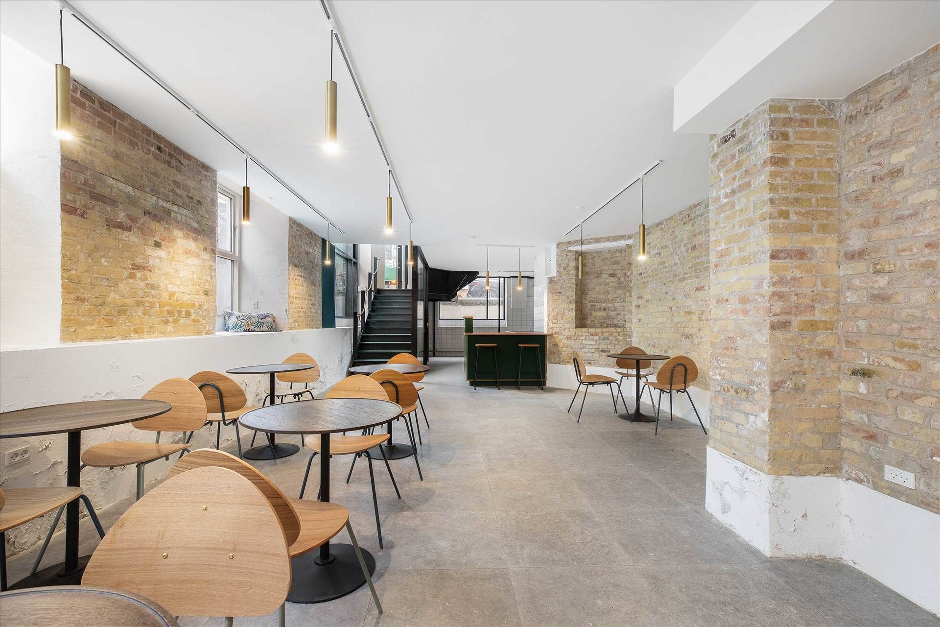 Køkken med rundt bord og stole samt høj bardisk med højstålene og stole på loftet