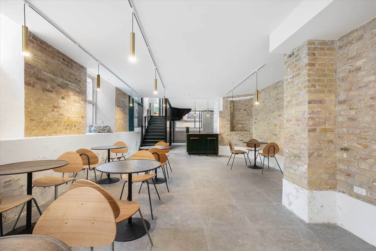 Køkken med rundt bord og stole samt høj bardisk med højstålene og stole på loftet