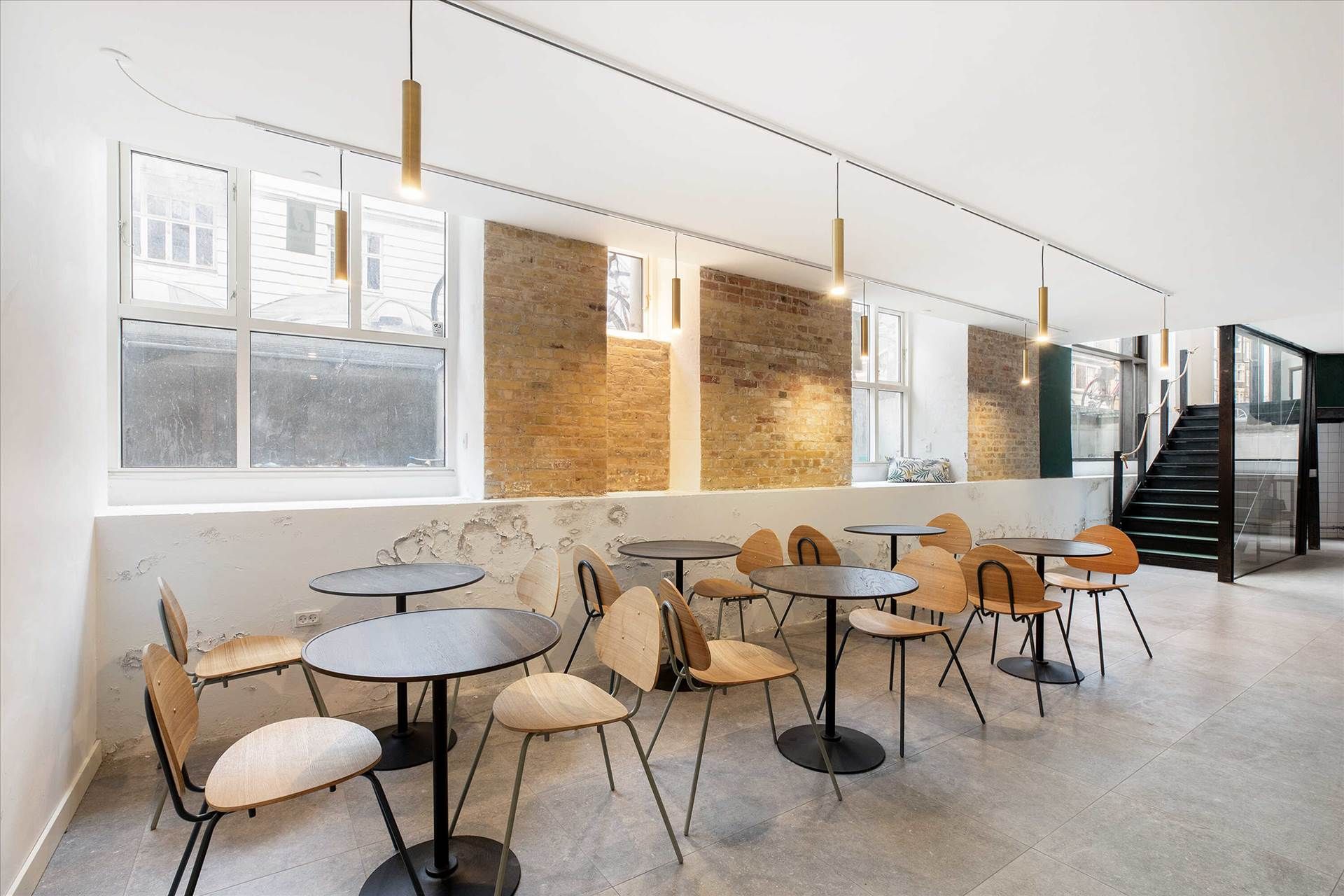 Møbelserie med rundt bord og stol i en café med møbler og vinduer i baggrunden