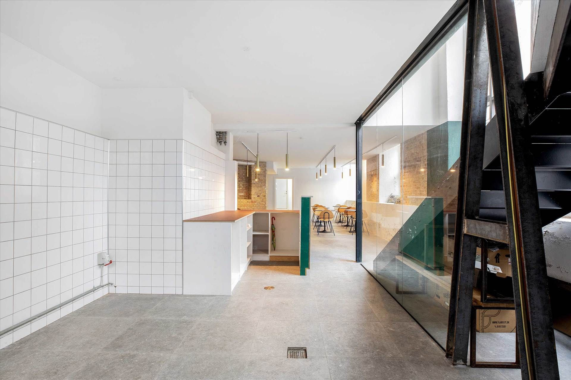 Indenfor et moderne kontor er der hvide vægge og lofter, hvor lysekroner hænger. Værelset er delt af en grøn sektion, og der