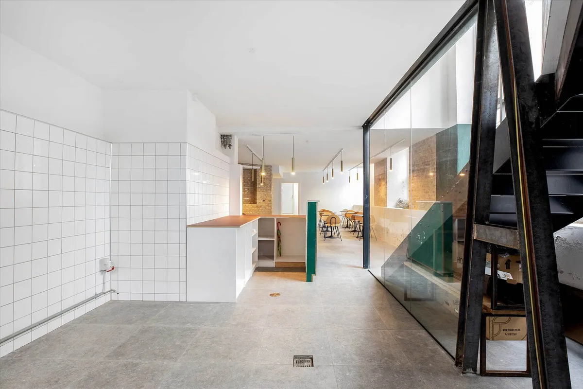 Indenfor et moderne kontor er der hvide vægge og lofter, hvor lysekroner hænger. Værelset er delt af en grøn sektion, og der