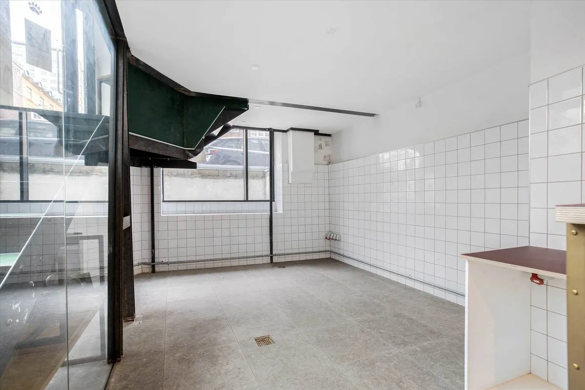 Store rummelige lokaler med flere vinduer og en åben dør til forretning med et stort glasvindue