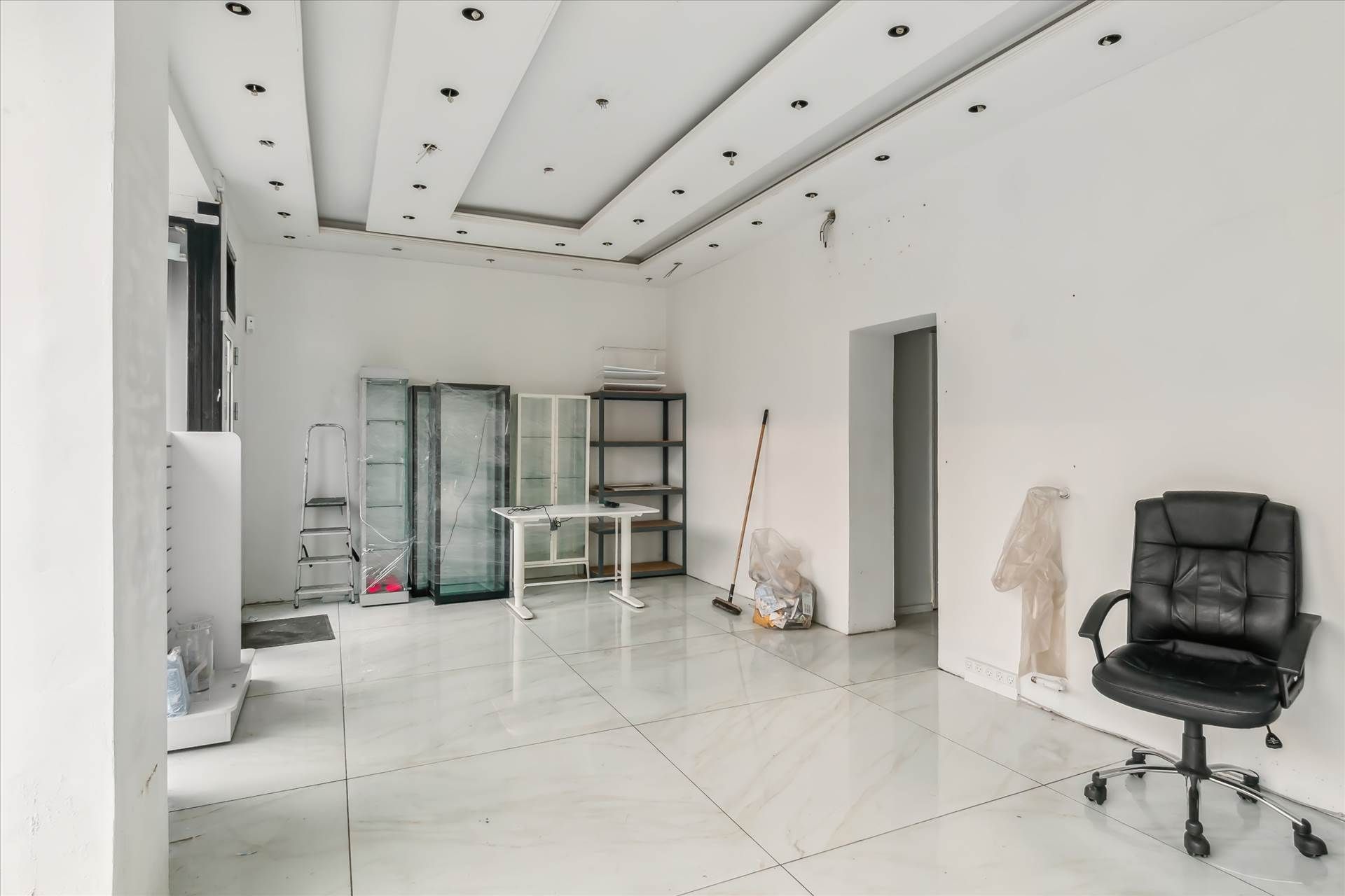 En tom hvid malet butik med gulvtæppe og møbler og apparater som er liggende rundt.