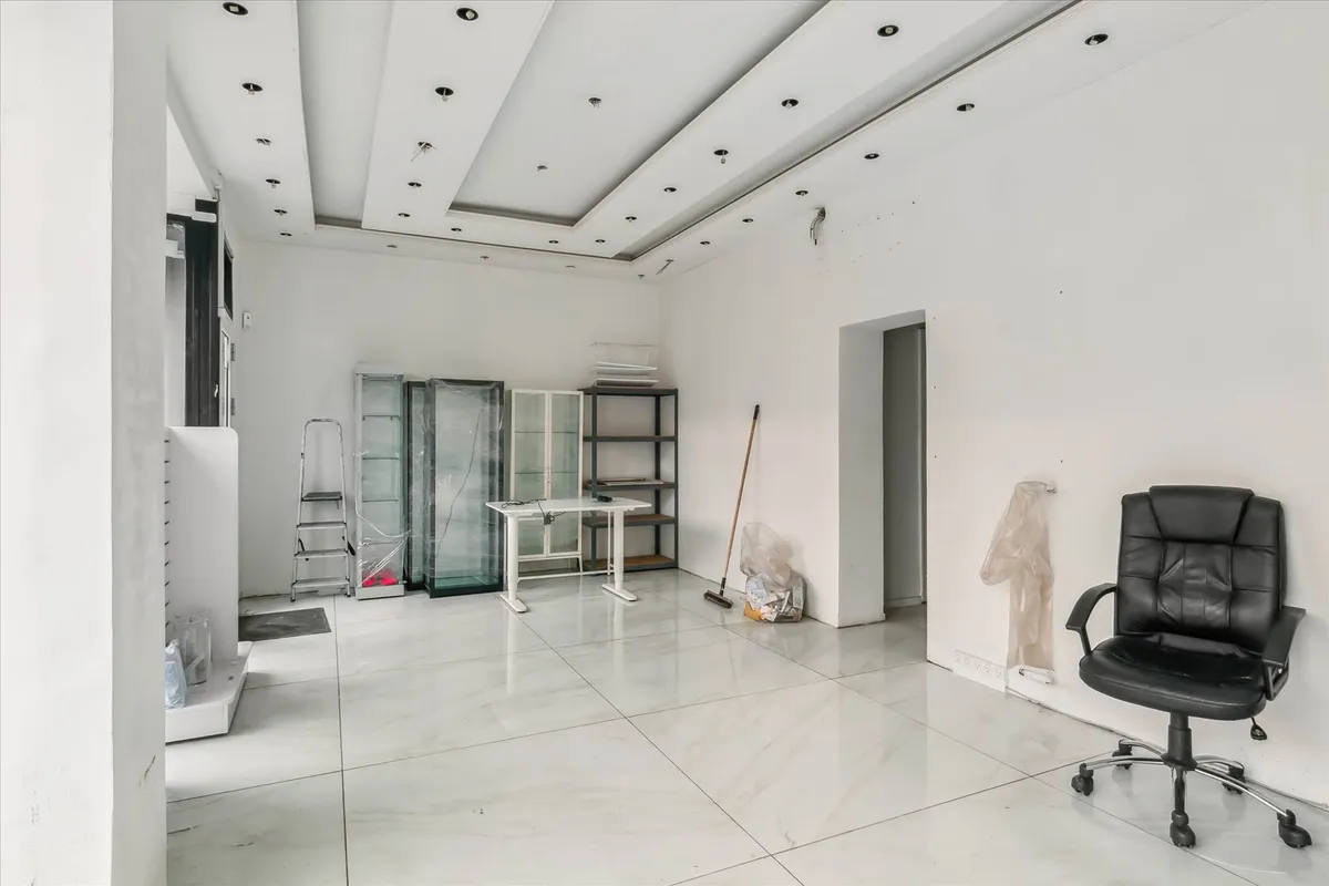 En tom hvid malet butik med gulvtæppe og møbler og apparater som er liggende rundt.