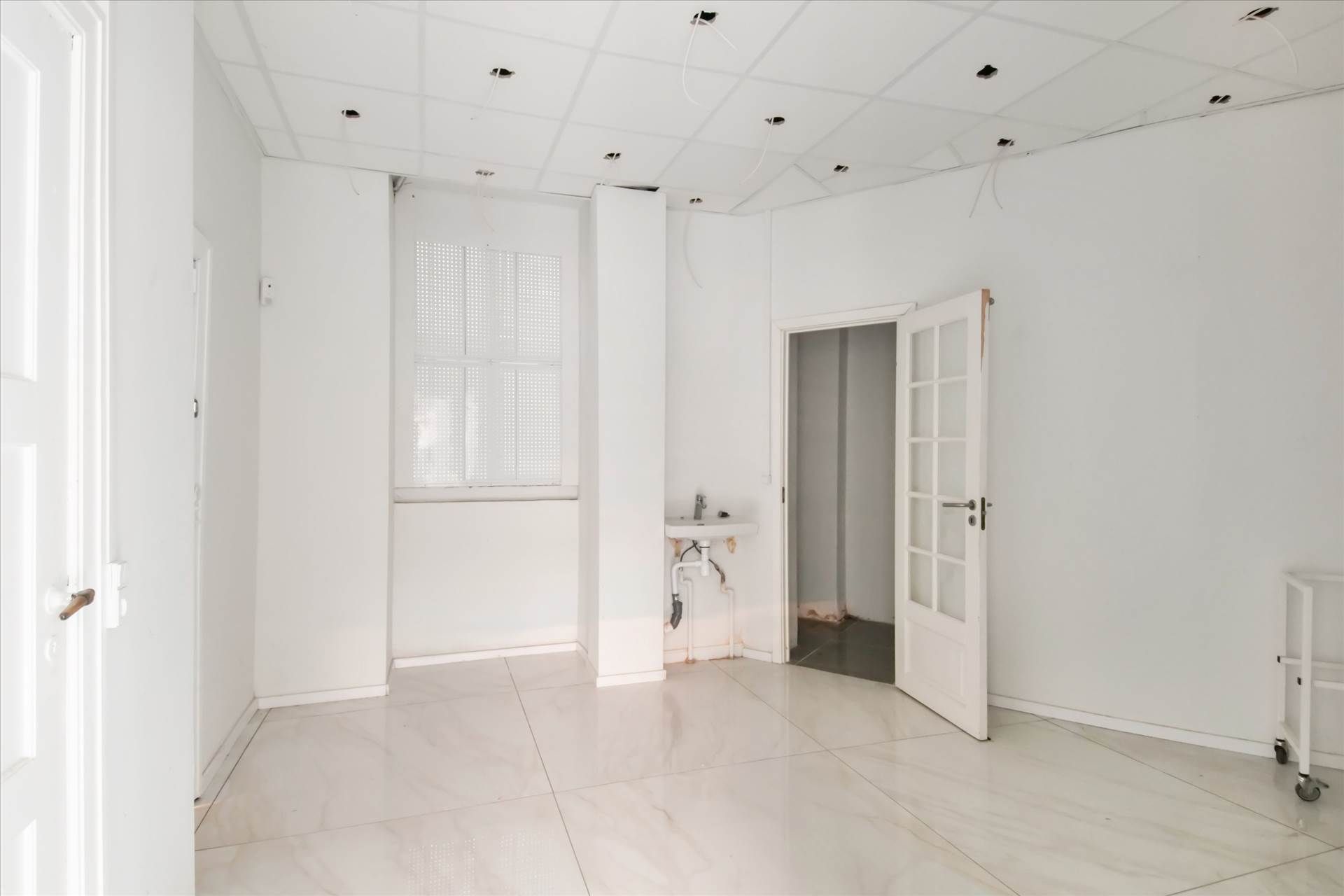 Store butikslokaler med højt til loftet og hvide vægge i en simpel indretning med gulv og loftsplader