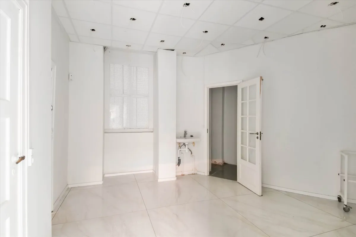 Store butikslokaler med højt til loftet og hvide vægge i en simpel indretning med gulv og loftsplader