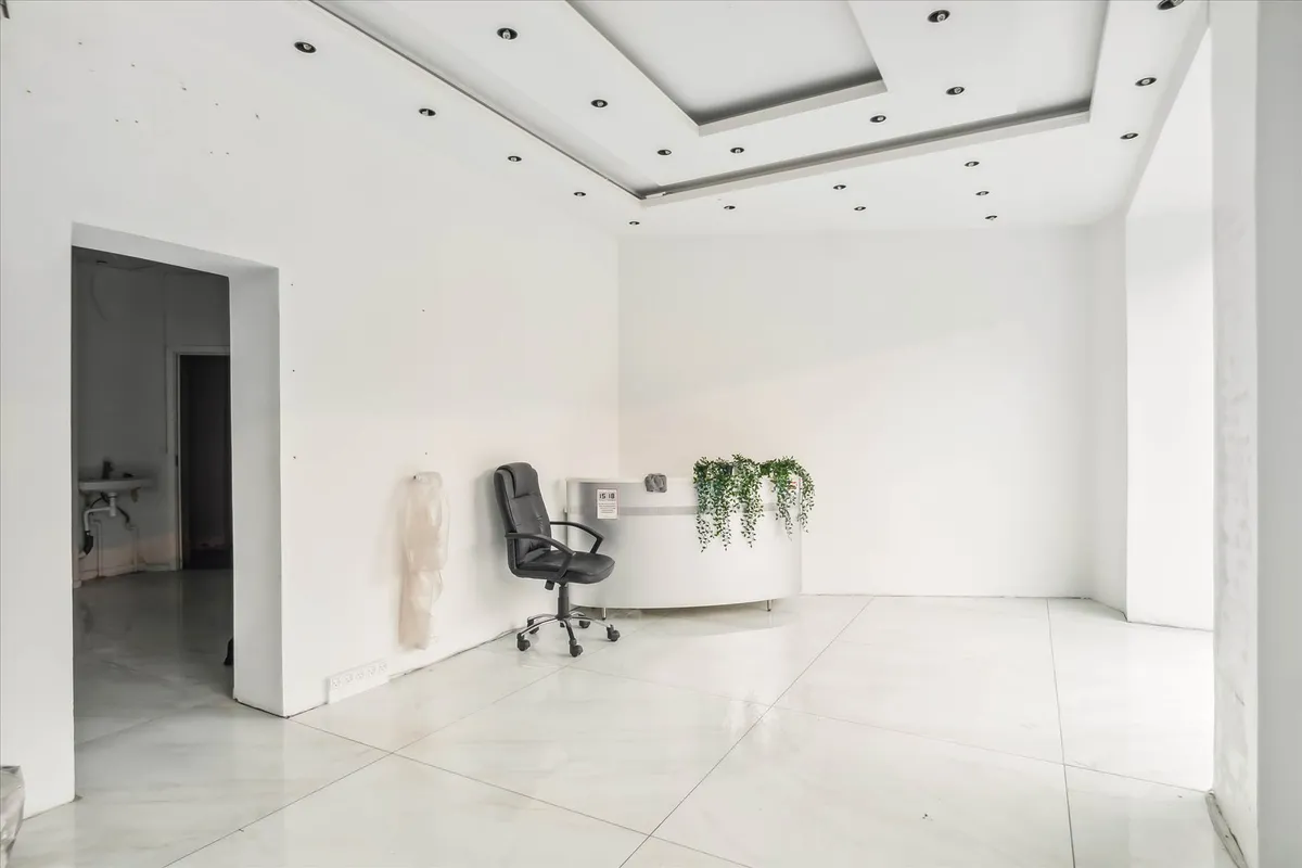 En tom hvid stue med en hvid stol og et hvidt bord med planter og en stribet skilt