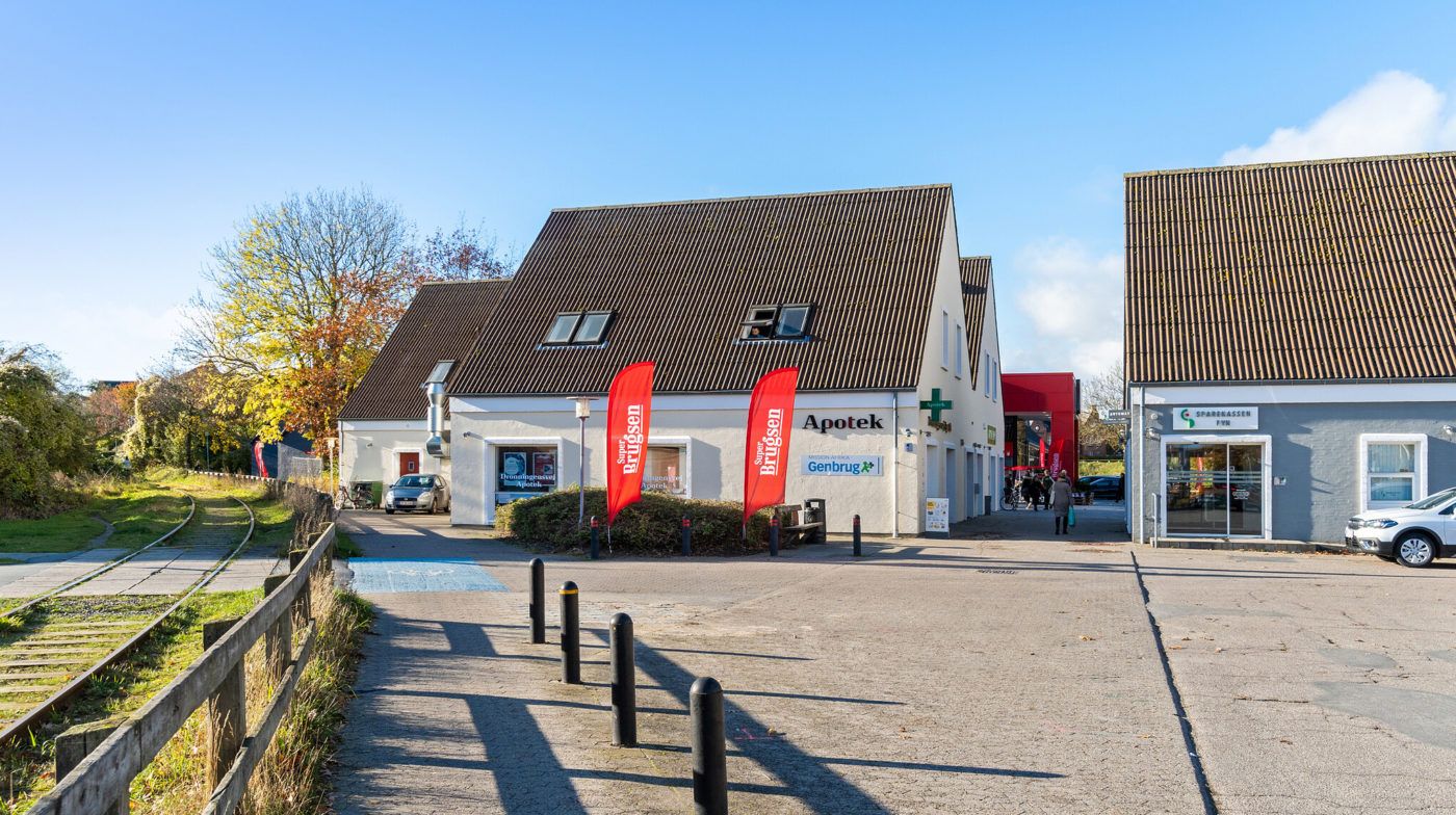 Apoteket ligger ved siden af Sparekassen og Genbrug, og der er en jernbane i baggrunden