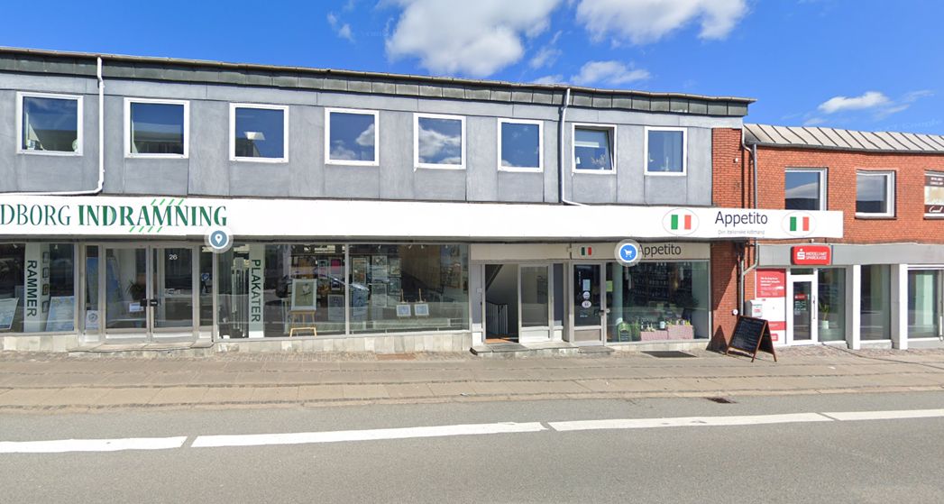 En toetagers bygning med flere butikker og et rødt bygning med vinduer og skilt med ordet Appetito