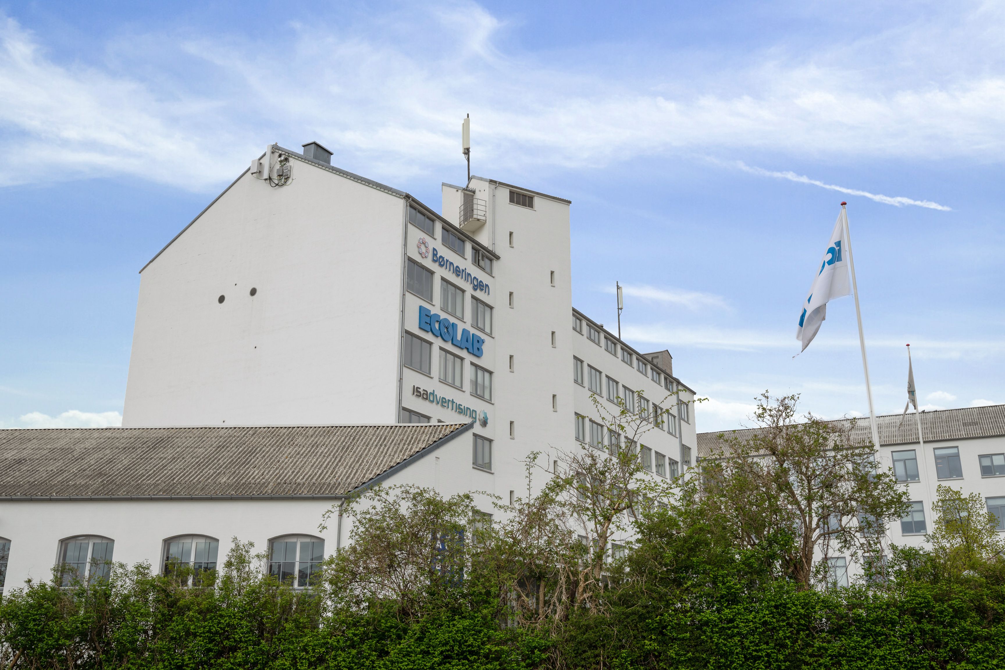 Moderne højhus med reklameskilte Ecolab og Børneringen samt dansk flag på flagpæl bygningen er nyt, lyst og rummeligt med