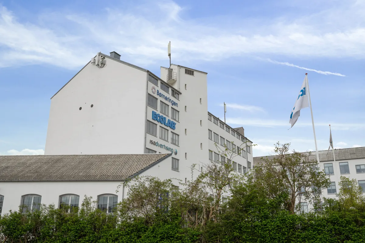 Moderne højhus med reklameskilte Ecolab og Børneringen samt dansk flag på flagpæl bygningen er nyt, lyst og rummeligt med