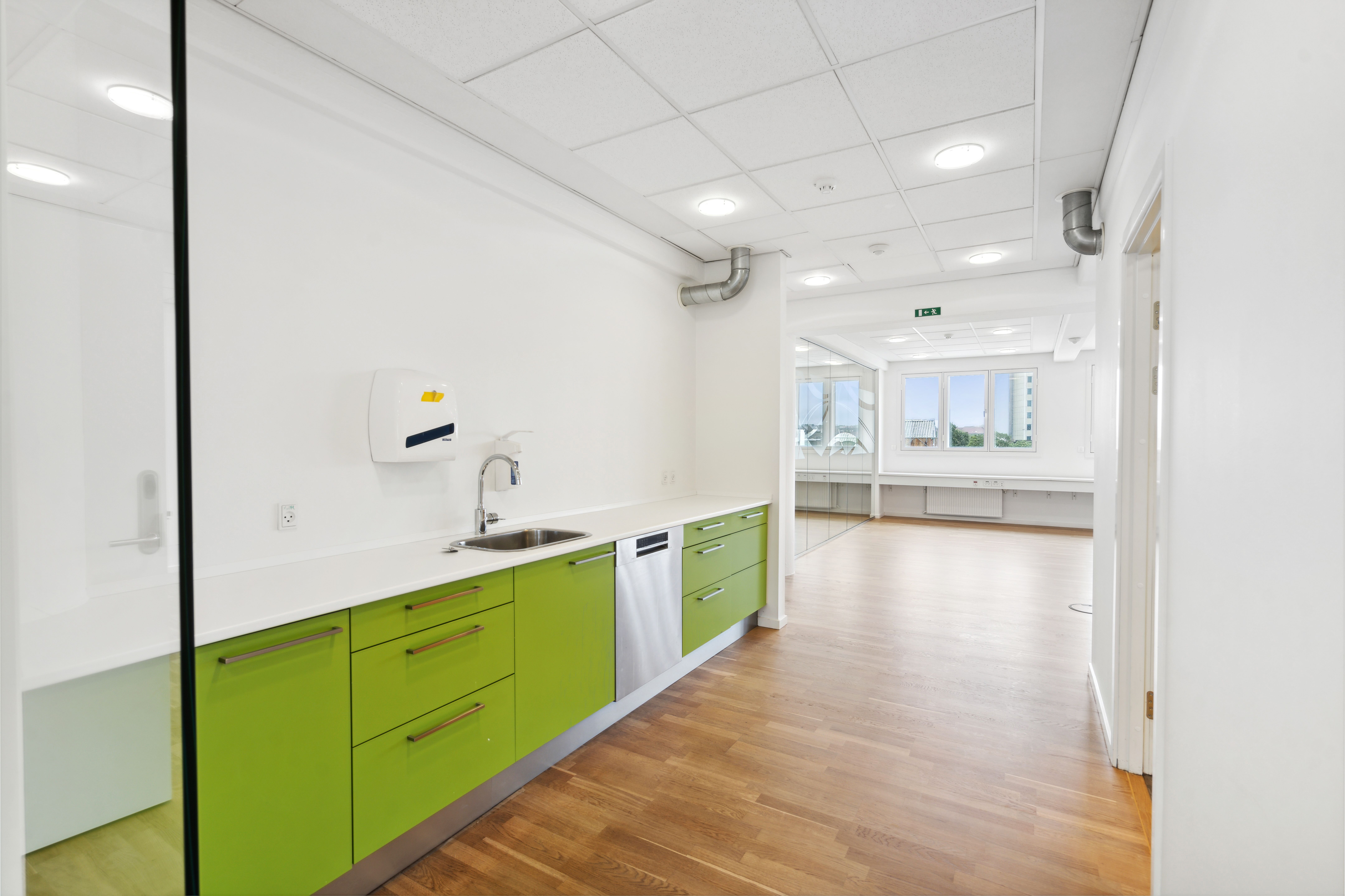 Rent og moderne køkken med lyse grønne skabe, hvidt arbejdsbord og en rustfri stål ovn placeret ved siden af en vandhaner