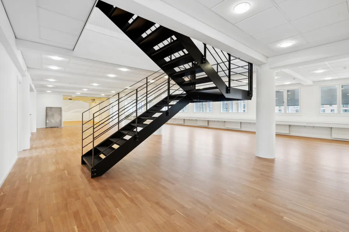 En to-etagers lejlighed med højloft og trægulv er klar til indflytning og har et moderne trappedesign