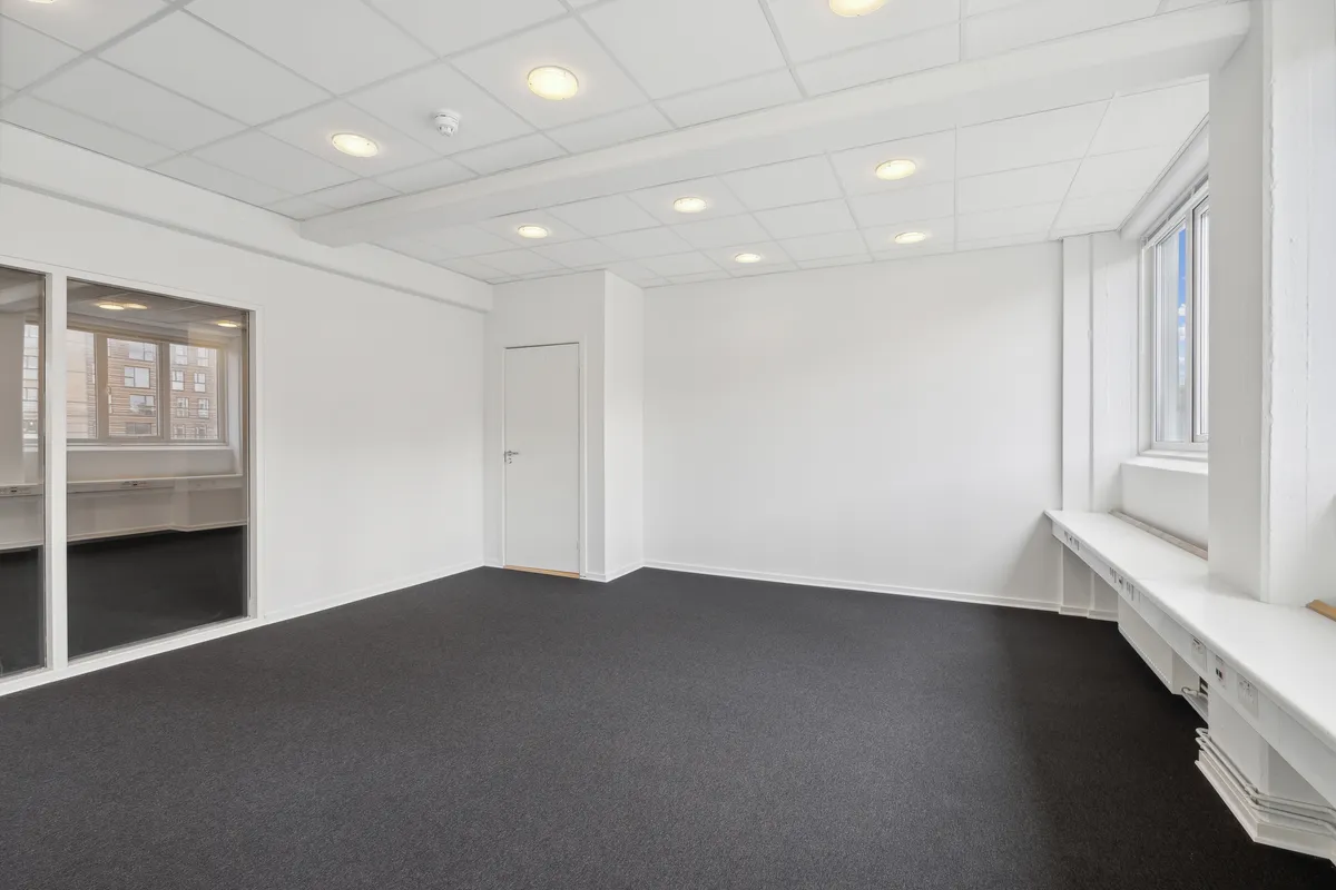 Lejemålet i Valby med hvide vægge og mørke gulve, glasdøre og vinduer med sollys, hvide lofter med indlejrede runde