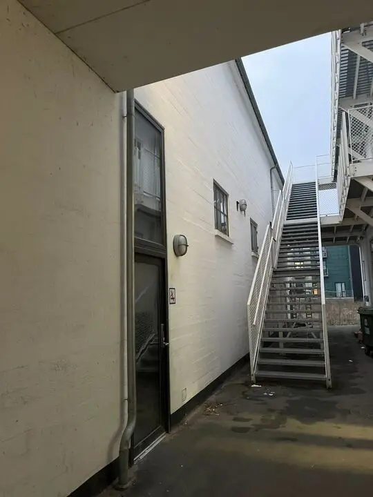 Sted med en glasdør og et trappeled til næste etage. Et rødt skilt og en iltslange er synlige.