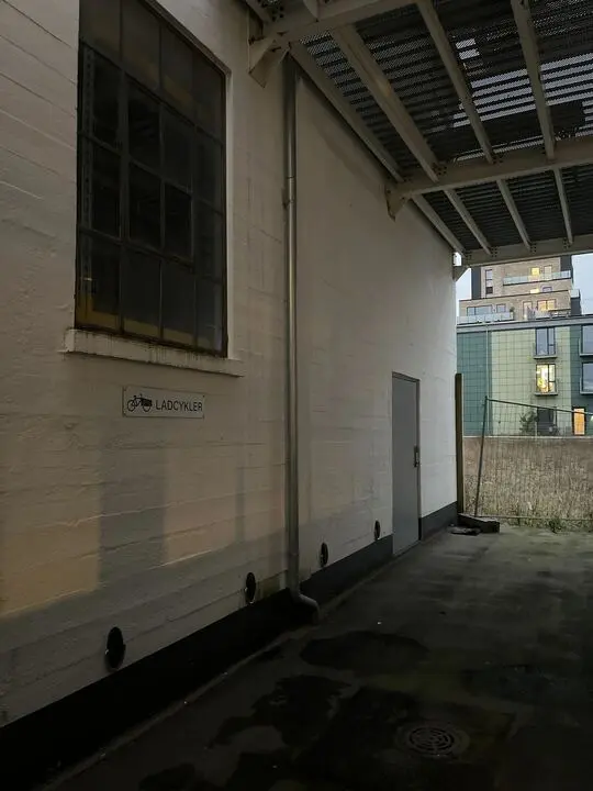 En lagerhal med en hvid væg og en glasvindue samt et skilt med teksten "LADYCYKLER" og et ikon af en cykel