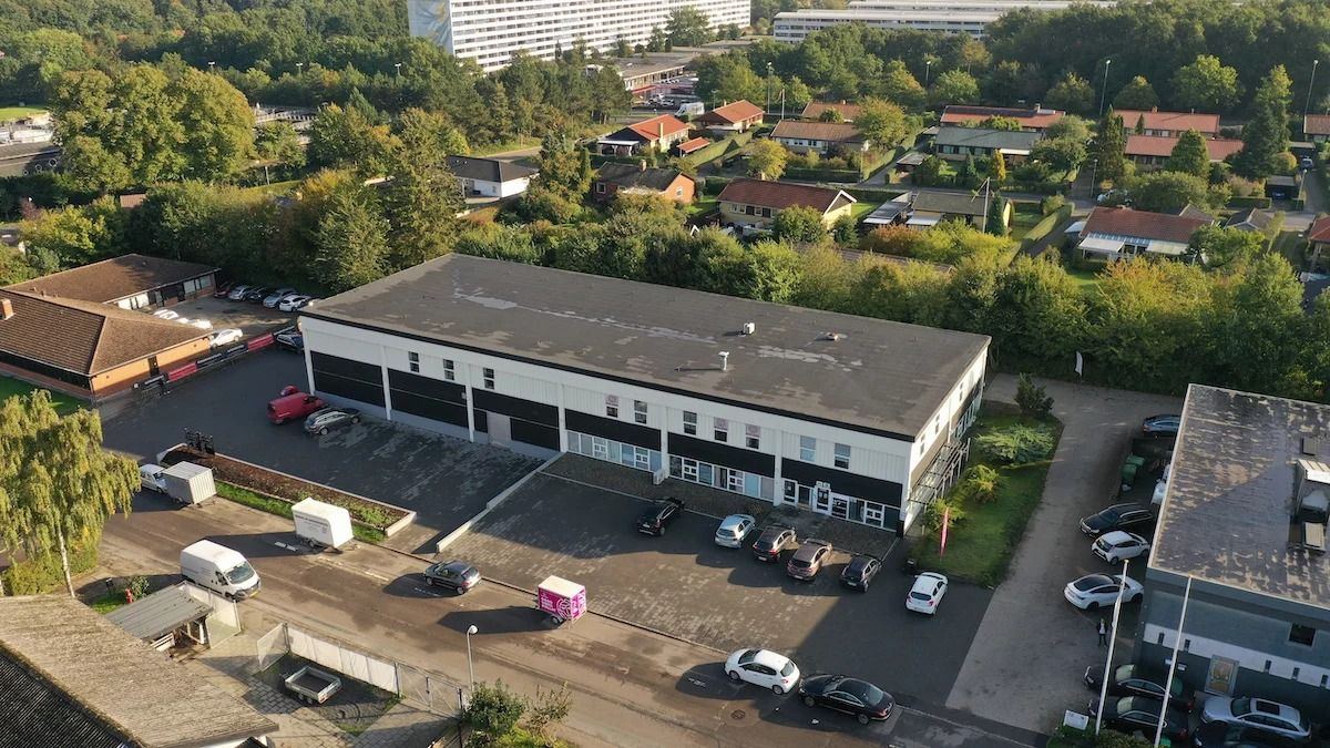 Hørsholms erhvervsområde med erhvervsejendomme, bilparkering, veje og busser i baggrunden