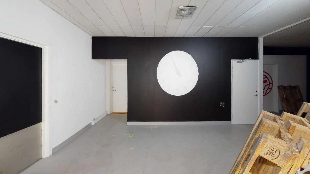 En tom kontorvæg med runde hvide cirkler og hvid dør med rødt logo på højre side af rummet