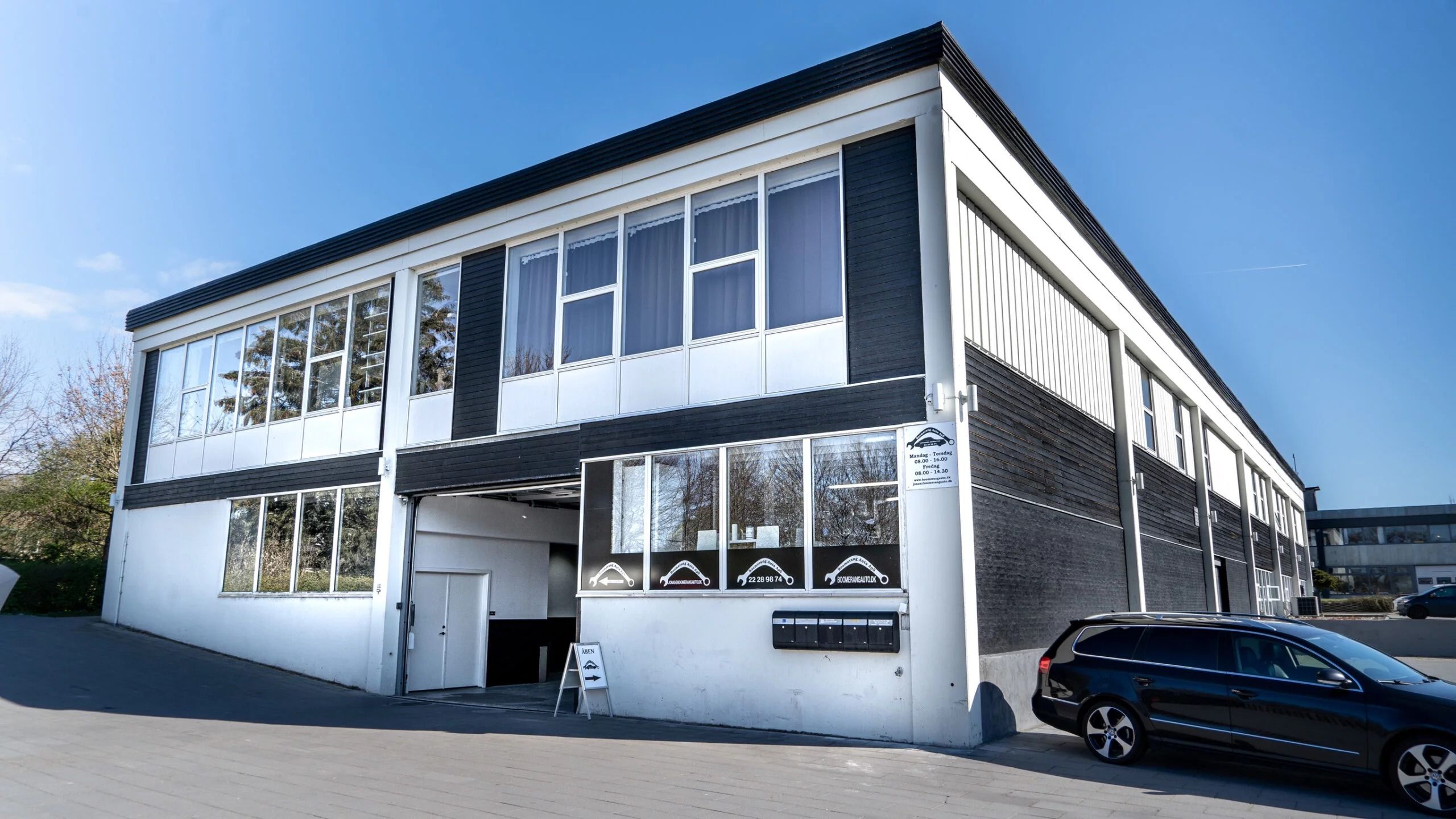 Hørsholms erhvervsområde med hvid og sort bygning og garagedør med skilt og bil foran