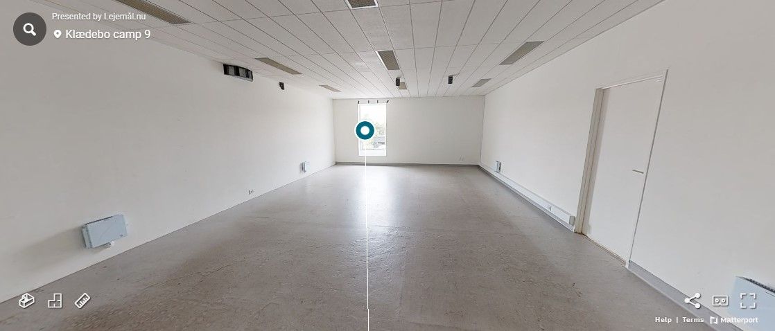 Tomt lokale i erhvervsområdet med hvide vægge, lysegrå gulv og hvide døre. Loftet er hvidt med indlejrede lys og