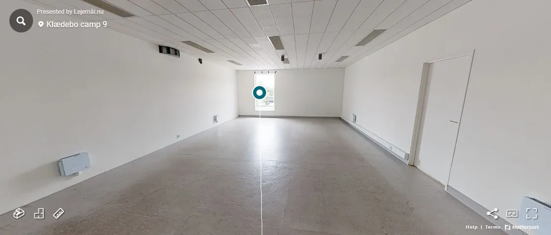 Tomt lokale i erhvervsområdet med hvide vægge, lysegrå gulv og hvide døre. Loftet er hvidt med indlejrede lys og