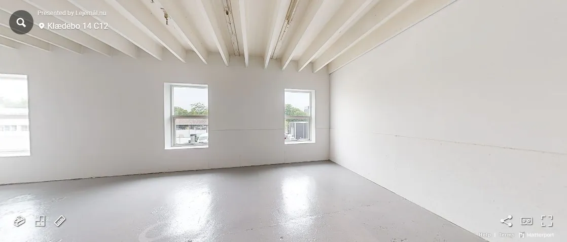 Ledig rum med hvide vægge og lofter, tre vinduer og to lystbøsser i bunden af billedet.