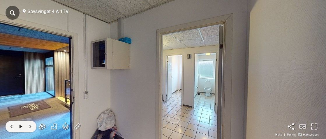 Gå ind i et rum med hvide vægge og gulv med firkantede fliser, og se en toiletdør og en toilet i et lille badeværelse. Se en