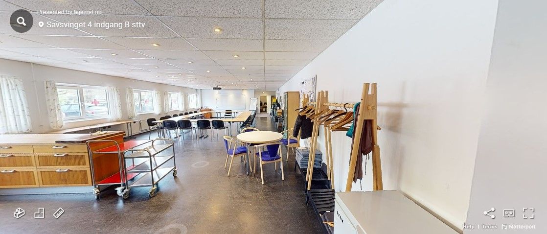 En tom kontorlokal i Savsvinget 4 med hvide vægge, loft og gulv samt træhylder med tøj og stole og borde i enden af lokalet