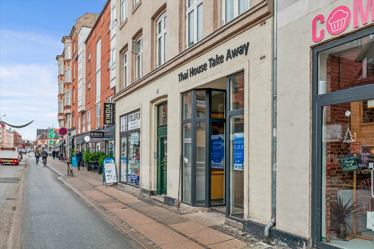 Butik med reklameskilt "Thai House Take Away" og "B'India" på gaden Amagerbrogade og en cykelparkeringsplads med to cykler