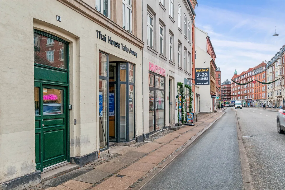 Butik med skilt Thai House Take Away og en grøn dør i en gågade i København med en bil og mennesker i baggrunden