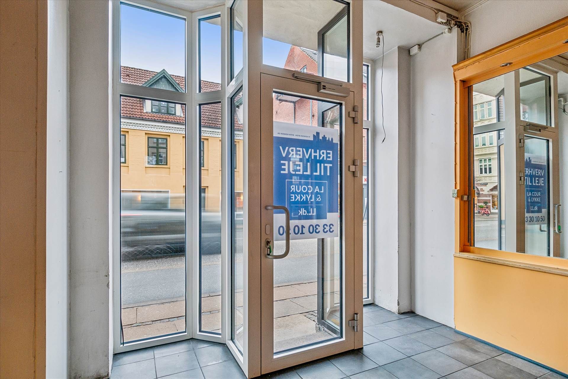 En stor åben dør til en butik med en skrift, der læser: Lejlighed til leje i København.
