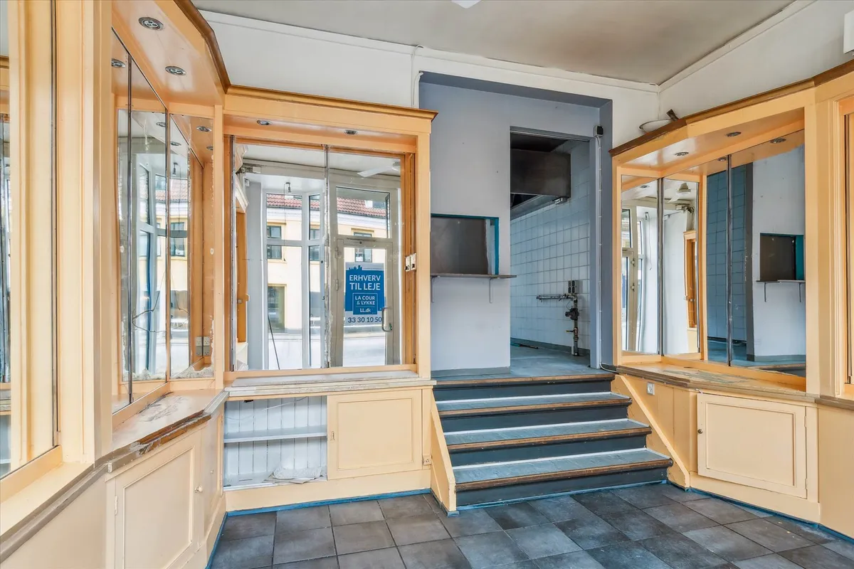 Moderne fin lejemål i stueetagen på Amagerbrogade med store vinduer, gulv og træpaneler, stiger op til kælder