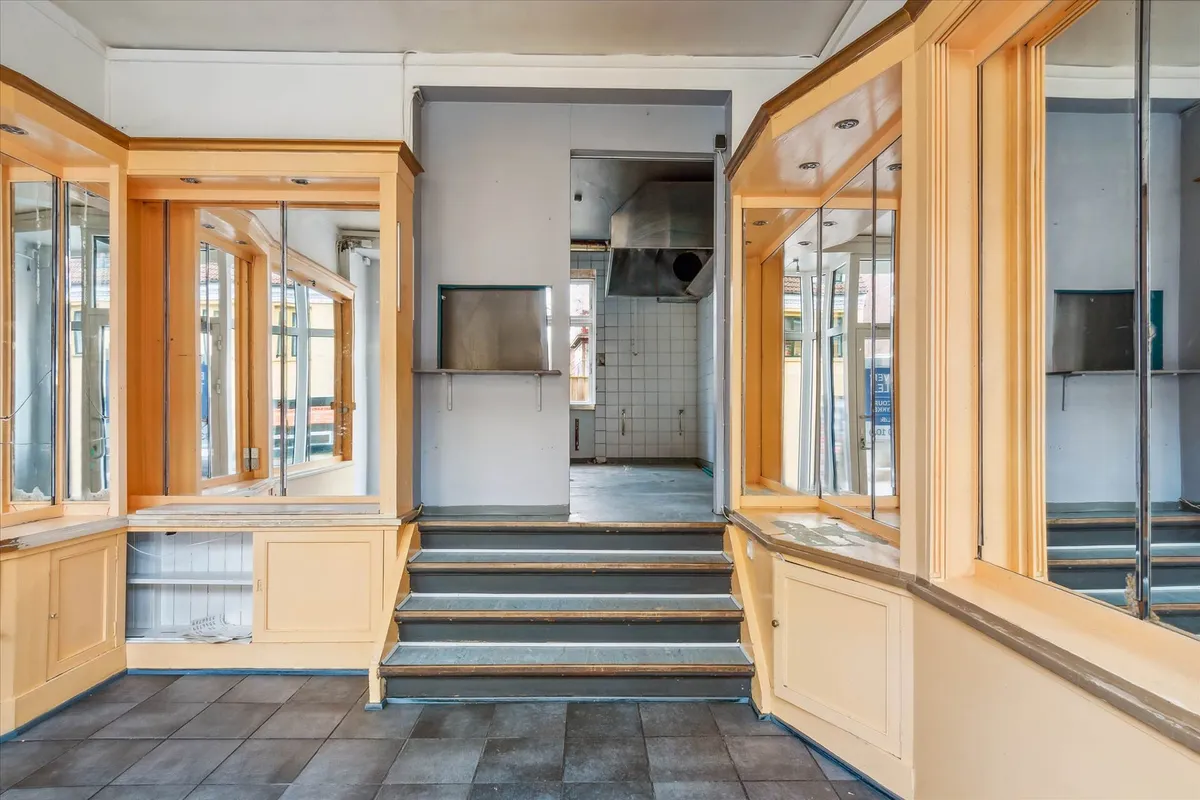 Lejlighedsbutik med store vinduer og trapper, gulv og vægge i beton og træ, tage med loftslampe