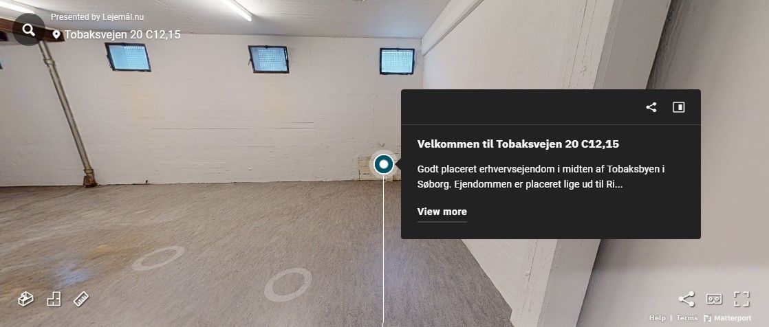 Et tomt rum med tre vinduer og en lysekrone. Der er markeret en cirkel på gulvet og et tekstfelt med tekst og knapper