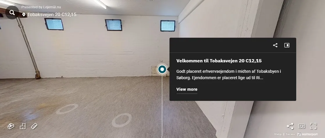 Et tomt rum med tre vinduer og en lysekrone. Der er markeret en cirkel på gulvet og et tekstfelt med tekst og knapper