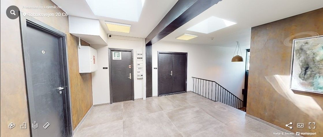 Kortere gange med tre døre, hvoraf to er lukkede og en er åben, og gulv og vægge er lavet i beton og metal