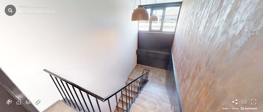 Trappe med mønstret væg og lysekroner. Adresse er Tobaksvejen 20 C6. Der er et ikon med opskrift på højre side.