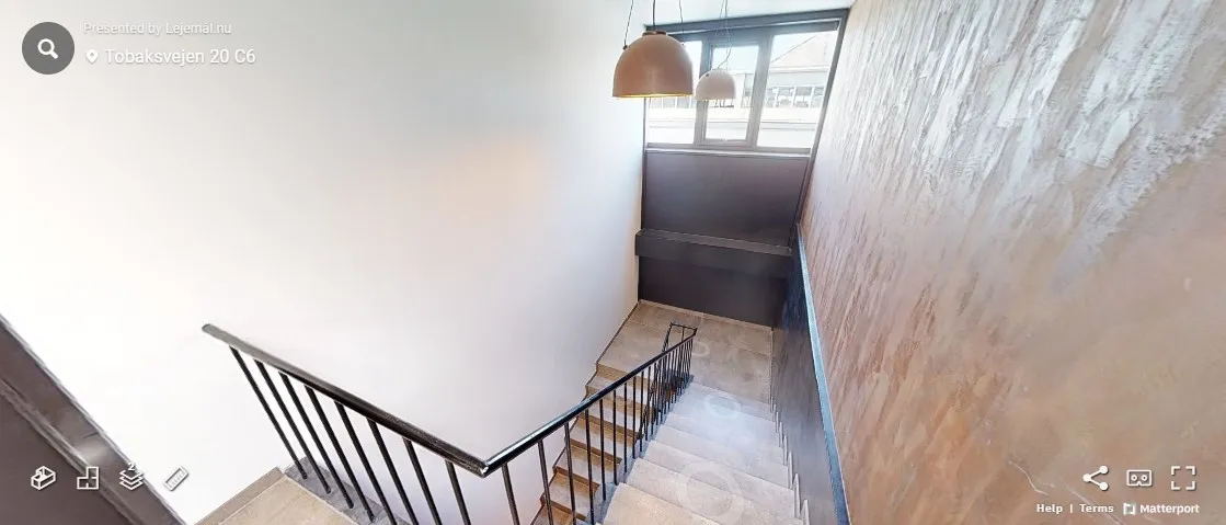 Trappe med mønstret væg og lysekroner. Adresse er Tobaksvejen 20 C6. Der er et ikon med opskrift på højre side.