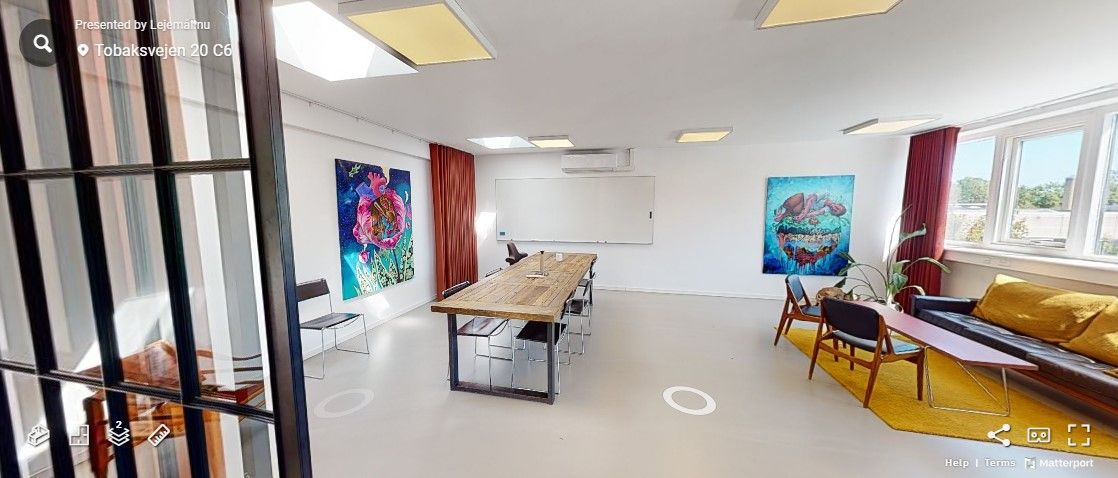 En mødelokale med hvidt loft og vægge, lysekroner, moderne møbler, skrivebord, sofa, vinduer og malerier på væggen