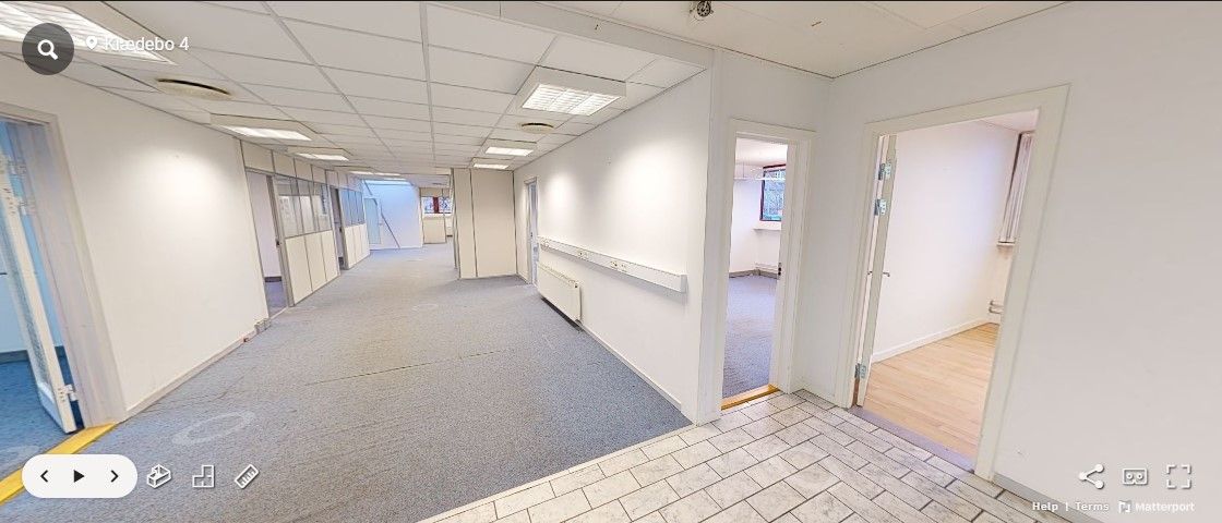 En tom, velholdt korridor med hvide vægge og gulve i Hørsholm. Der er åbne døre og vinduer. Gulvet er lysegråt og