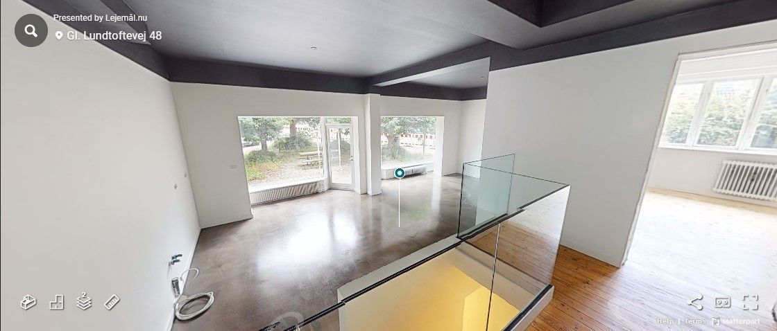 Foto af et smukt renoveret erhvervslejemål med moderne glastrapper og en stor terrasse med udsigt til en park. Lejligheden