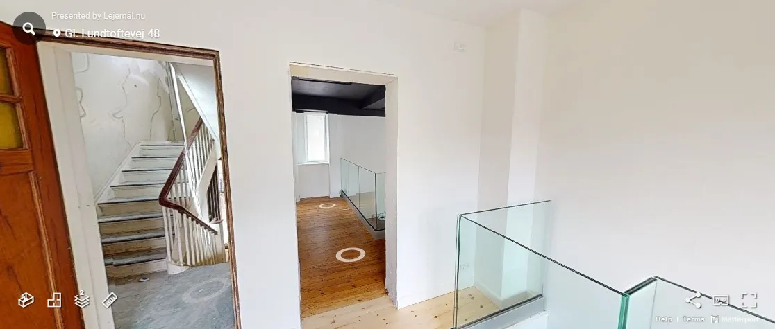 Interiør med glasgulv og hvide vægge samt trægulv og trapper. Glasskærm og trægulv i lyse værelser med indbygget stige.