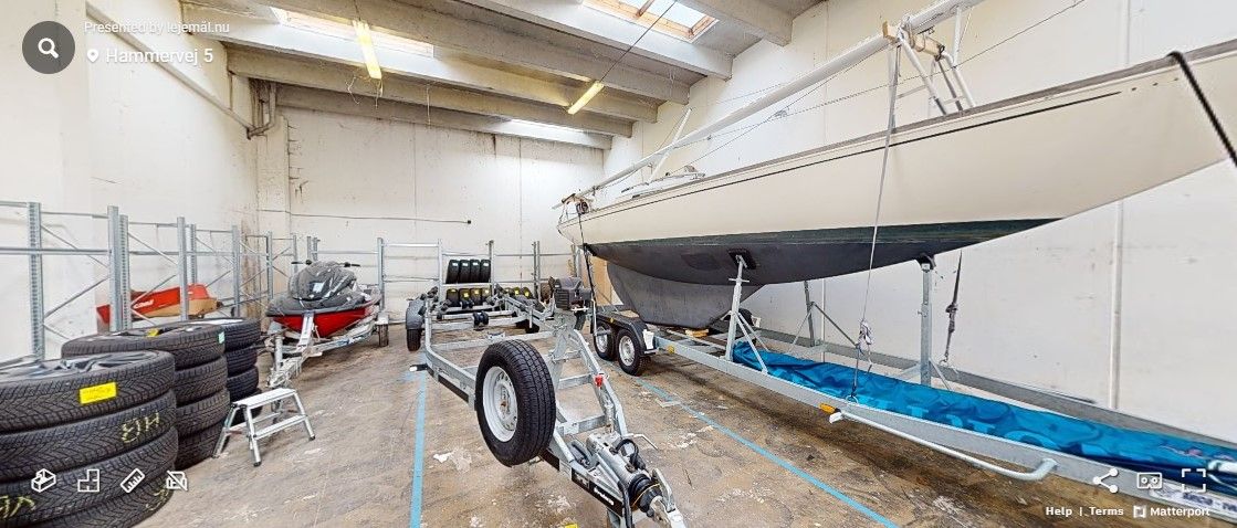 Garage med skib og slæbevogn, redskaber og gummibåd samt masser af dæk og hjul i en stor hall