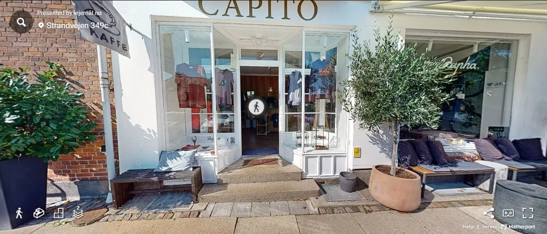 Indgang til butikken Capito med lyse ruder og træindgang. Planter og træer udenfor.