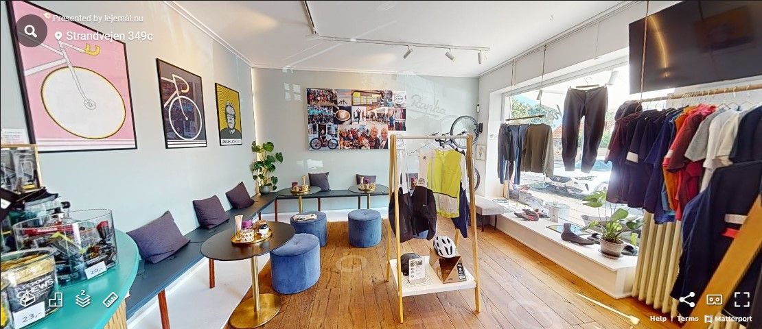 Et moderne møbelforretning med trægulve og høje lofter, fuld af tøj og sko, og dekorative vægpapir og kunstværker.