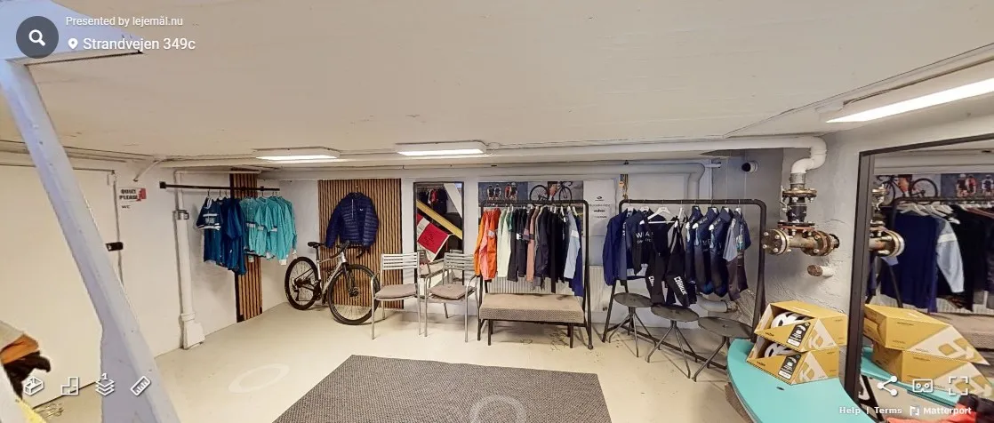 Rummelige lokaler med tøjvask, hvor der er tøj på væggene og tøj i vugger, samt tøjstativet med tøj og flere møbler