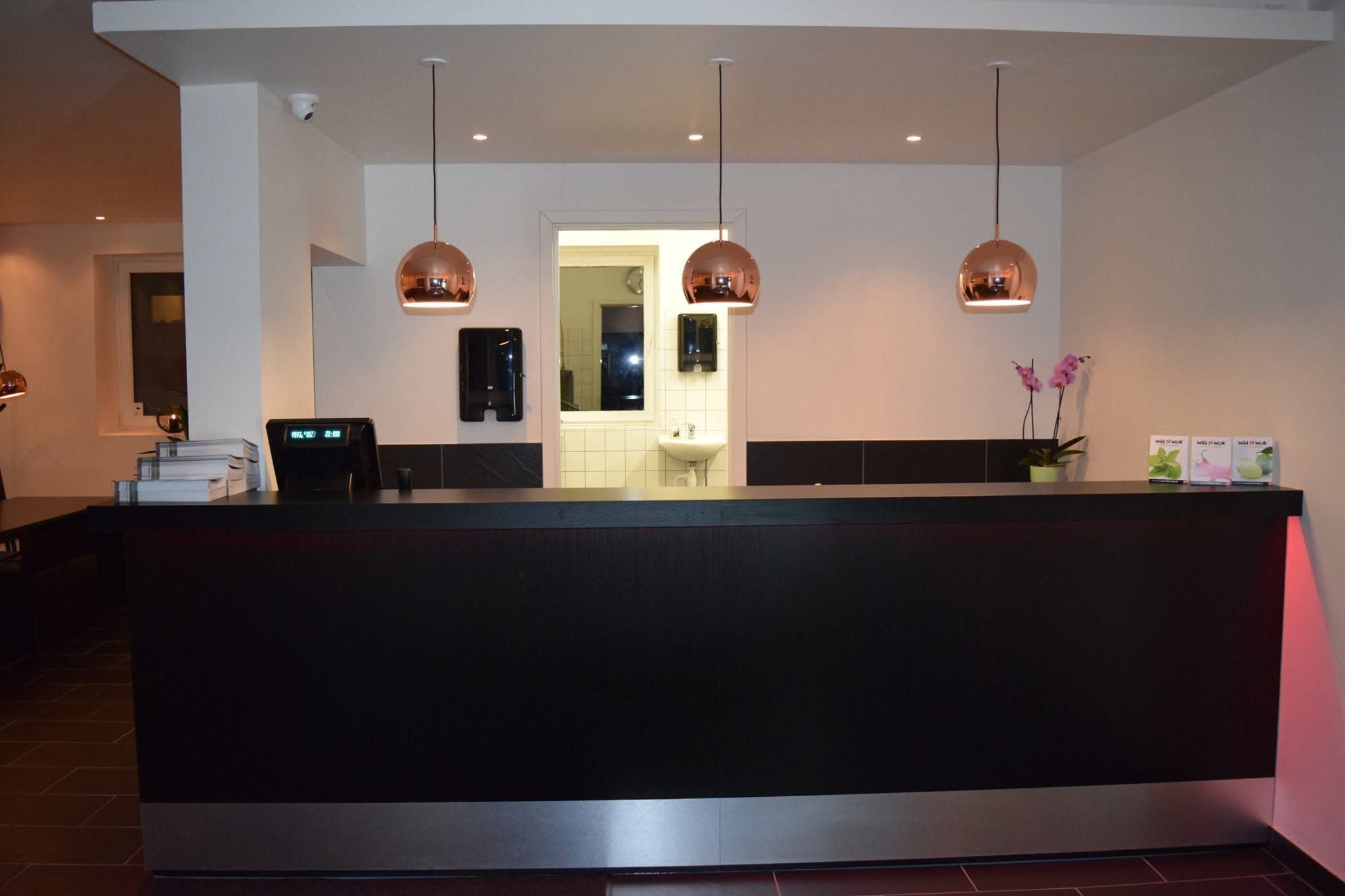 Sort og gulvmonteret salgssted med en blomst og 3 kobberkronleuchter. Et toilet med spejl og håndvask samt et skrivebord med