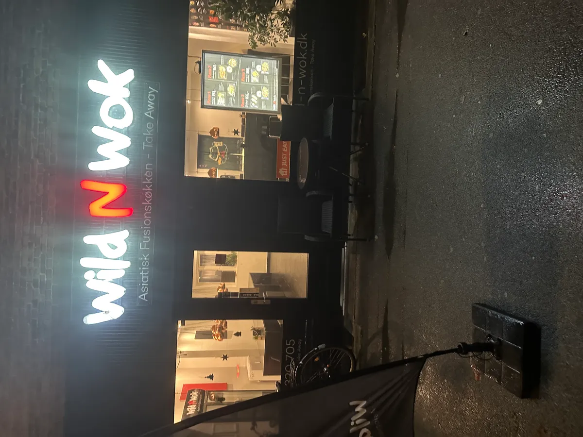 Thai restaurant Wild N Wok med stolpebord og menu overskrift. Kontakt os på 52526002 for takeaway og online bestilling.