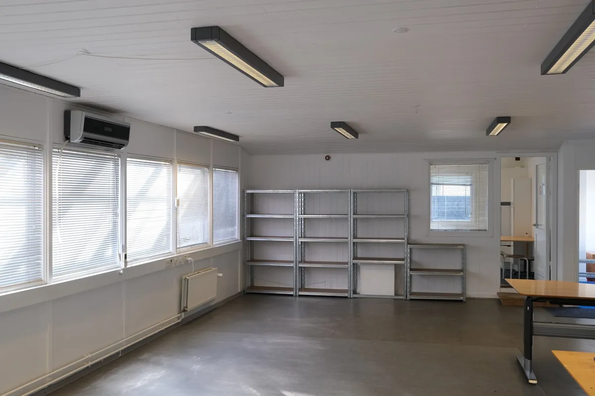 En tom lejlighed med vinduer og radiatorer og høje hylder i metall, lysekroner og klimaanlæg
