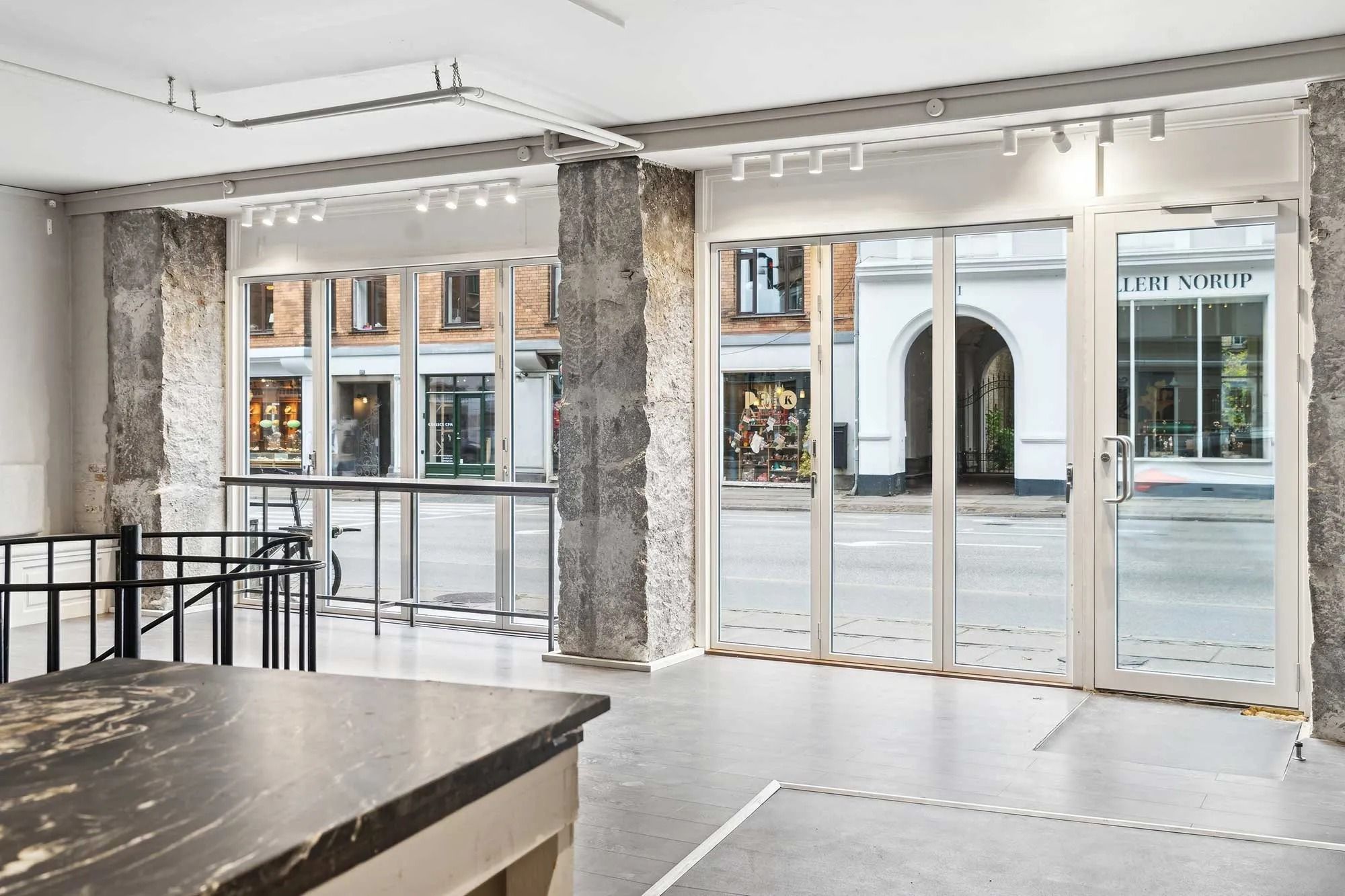 Store glasruder og lyse loftslampe på butikslejemålet på Gammel Kongevej med udsigt til gågade og gågade med en bred